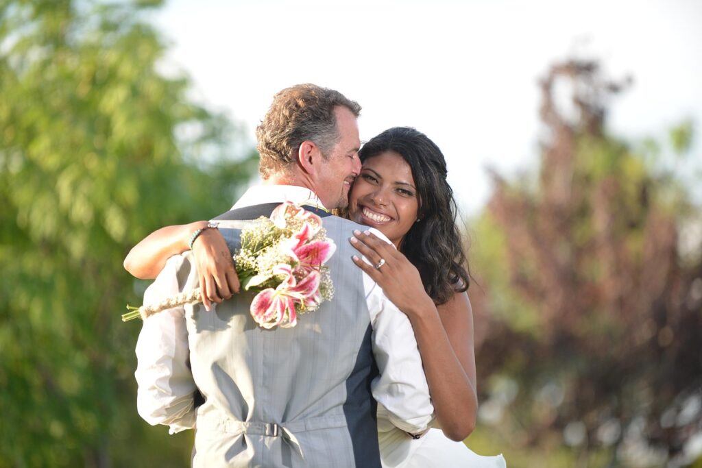 A newlywed couple hugging after their ceremony, smiling brightly, capturing the relief and joy that follows the emotions and stress of the wedding day.