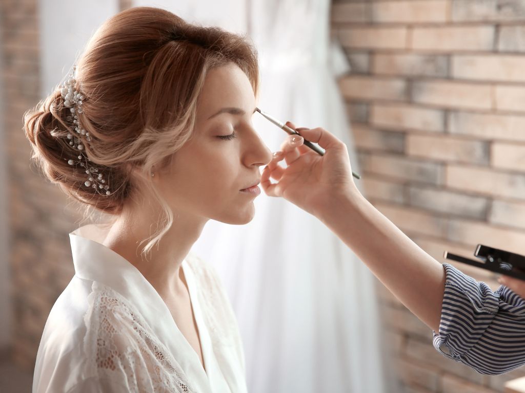 Bride preparations with professional makeup session, elegant hairstyle adorned with pearls for a tropical Caribbean wedding