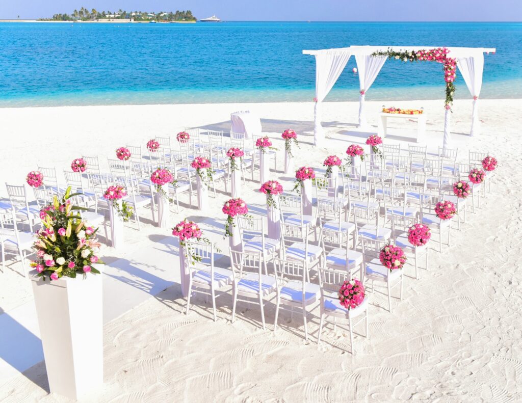 A wedding ceremony on a white sandy beach with the sea in the background.