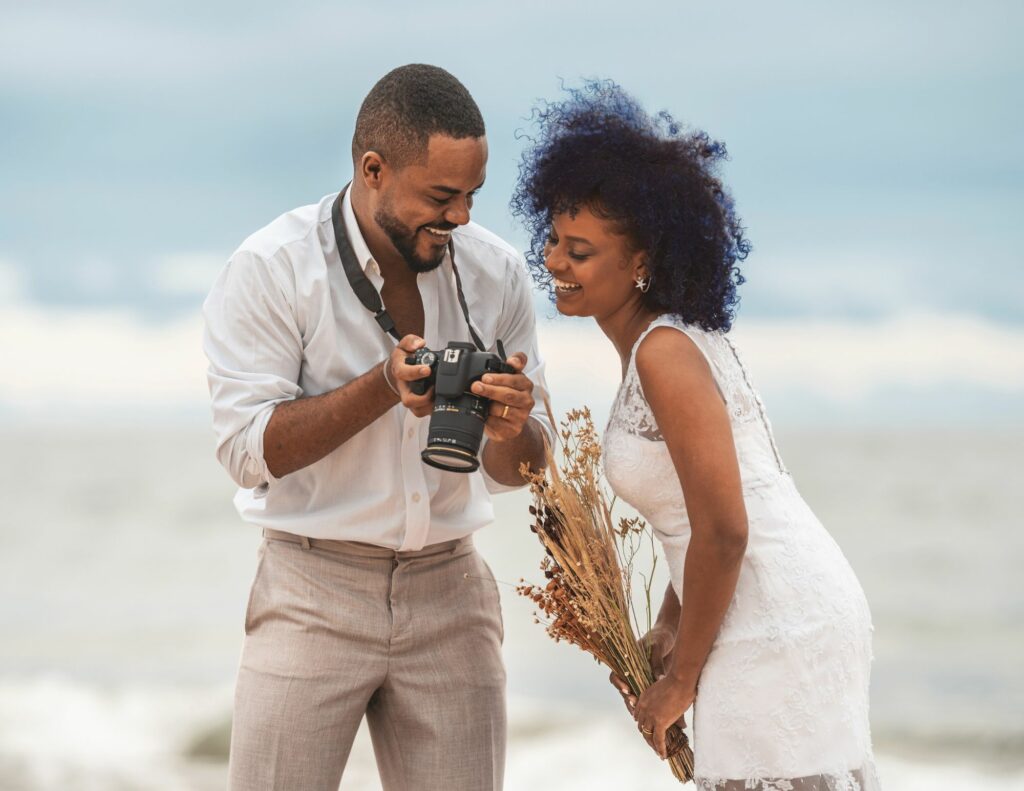 Newlyweds reviewing their wedding photos with professional photographer on Caribbean beach