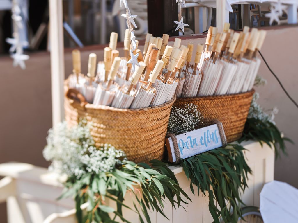 Parasols as guest favors arranged in baskets at an outdoor wedding.