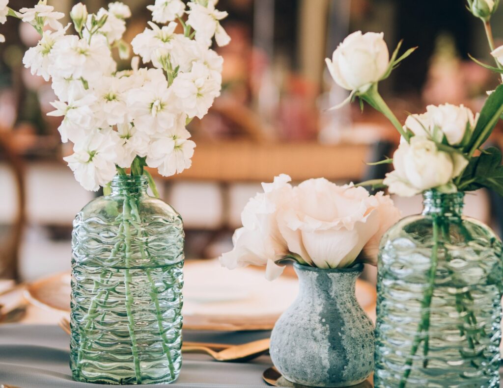 Focus on a table decoration with small green vases containing white flowers, combining simplicity and refinement.