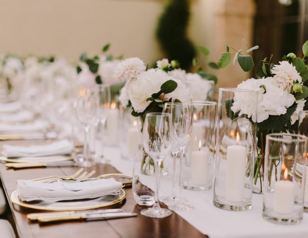 Wedding table elegantly decorated in a minimalist style, adorned with white flowers and candles.